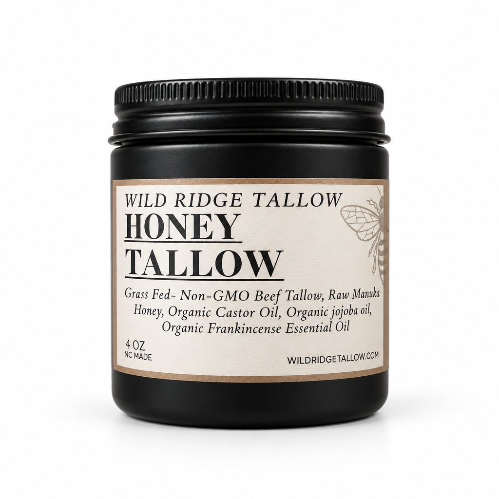 A jar of Wild Ridge Tallow Honey Tallow oil on a white kitchen countertop, with a stand mixer and white buckets blurred in the background.