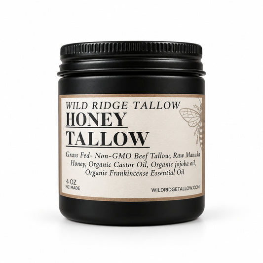 A jar of Wild Ridge Tallow Honey Tallow oil on a white kitchen countertop, with a stand mixer and white buckets blurred in the background.